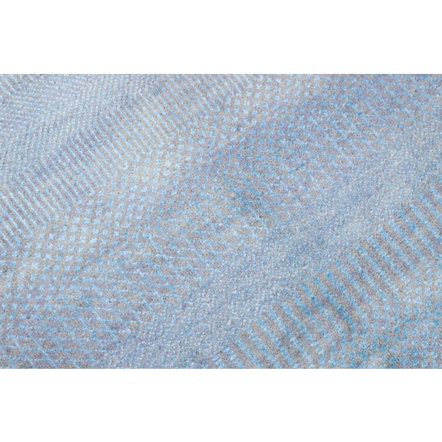 This long hand-knotted rug is made of wool. It features a subtle light blue color scheme accented by an all-over geometric...