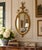 An elegant early 20th-century oval wall mirror in the Neoclassical Adam tradition, with a finely proportioned giltwood and...