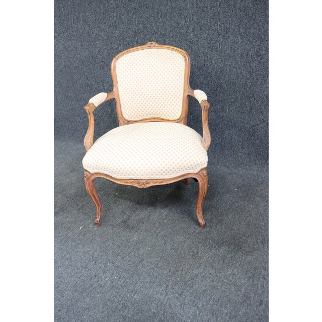 Early 1900’s Louis XV style open arm chair . Frame is made of solid cherry , floral carved accents , cream patterned fabric