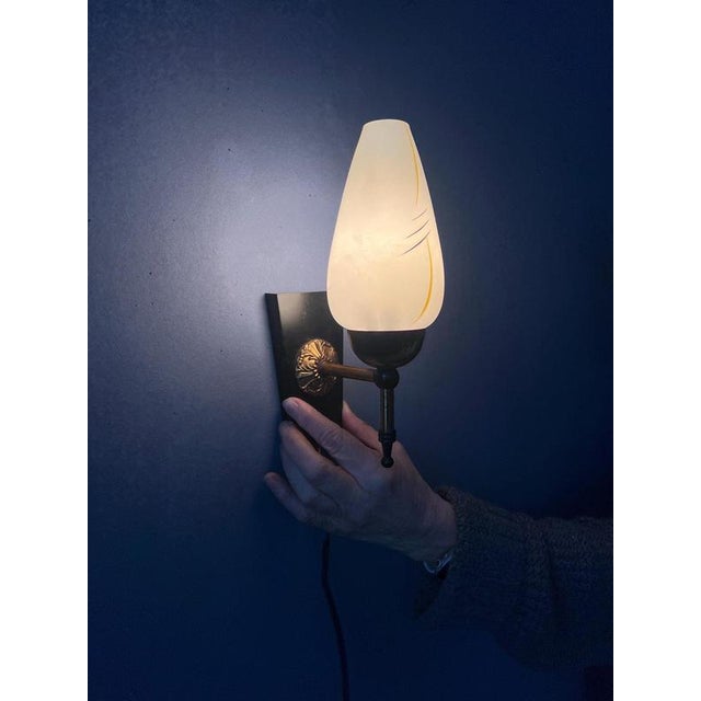 Vintage glass wall lamp with metal frame. The glass shade has a decorative pattern. The lamp requires one E14 lightbulb...