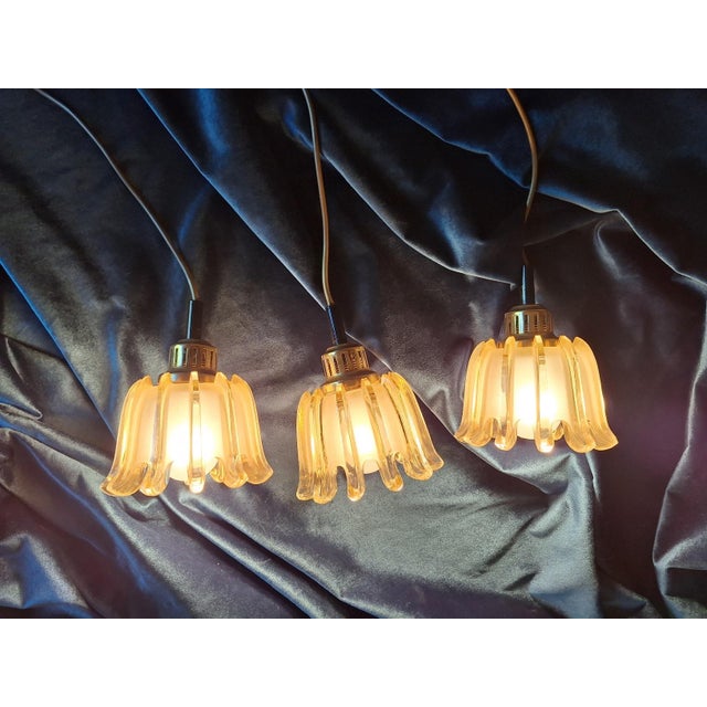 Set of 3 Doria mid century organically shaped pendant lights in brass and amber-colored frosted glass dating from the...
