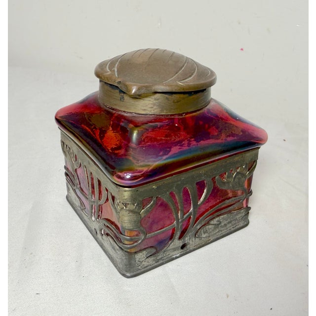 The Antique Carl Stolzle Austrian Art Nouveau bronze mounted red iridescent glass writing inkwell is a collectible piece...