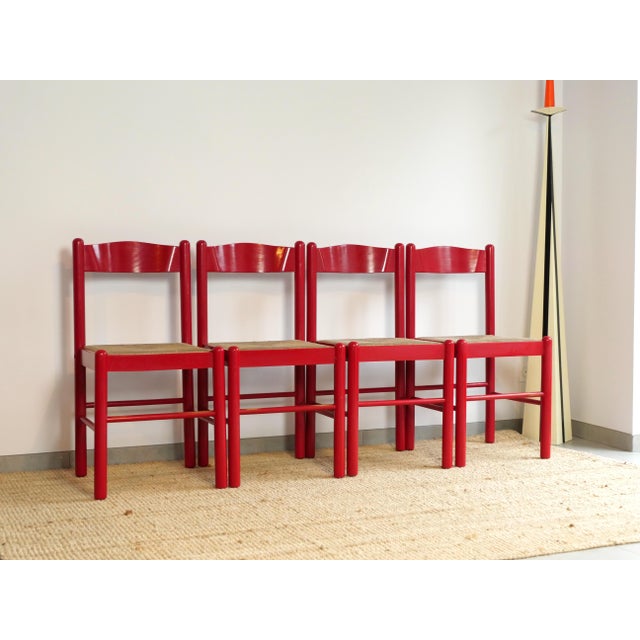 Set of four turned wooden chairs, entirely lacquered in a vibrant red. Cylindrical legs connected by stretchers and a...