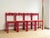 Set of four turned wooden chairs, entirely lacquered in a vibrant red. Cylindrical legs connected by stretchers and a...