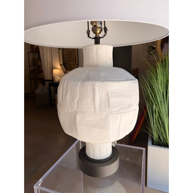 This contemporary table lamp makes a striking statement with its sculptural textured base and clean, modern silhouette....