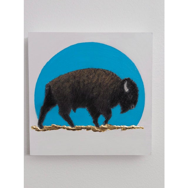 In "Blue Sunset," a solitary bison strides across a textured landscape, set against a striking blue circle that evokes the...
