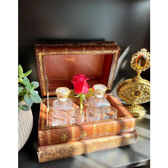 Beautiful, French gilt leather faux book liquor tantalus set with interior brass fittings. The set includes, 2 decanters...