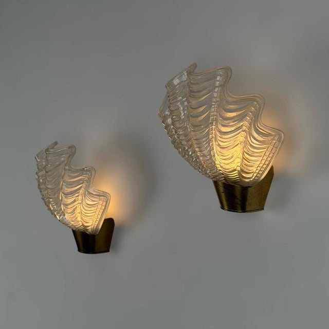 Elegant and sculptural, these rare wall sconces feature beautifully molded shell-shaped glass shades mounted on patinated...