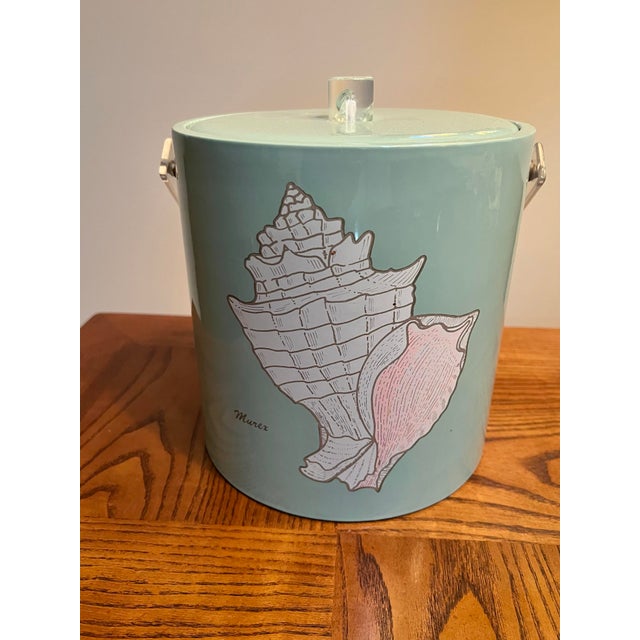 Vintage seashell-themed ice bucket & lid with a clear lucite handle. Features a image of a Murex seashell against a light...