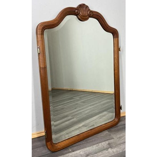 This Vintage French mirror presents a refined oak wooden frame with softly curved lines and a carved shell crest, offering...