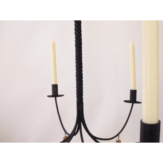 This hand made iron chandelier for candles has old, distressed wooden pendants.