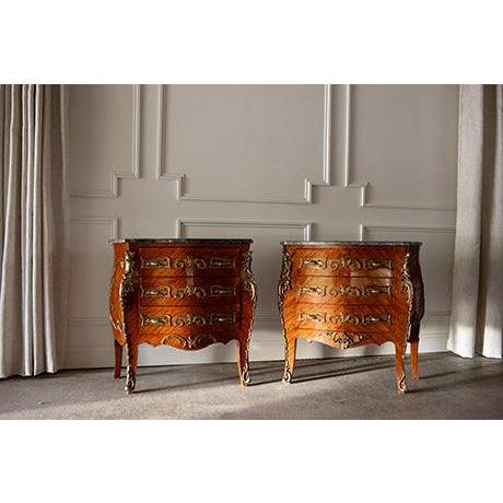 An elegant matching pair of French Louis XV style commode sauté chests of drawers. Features curved bombé shapes,...