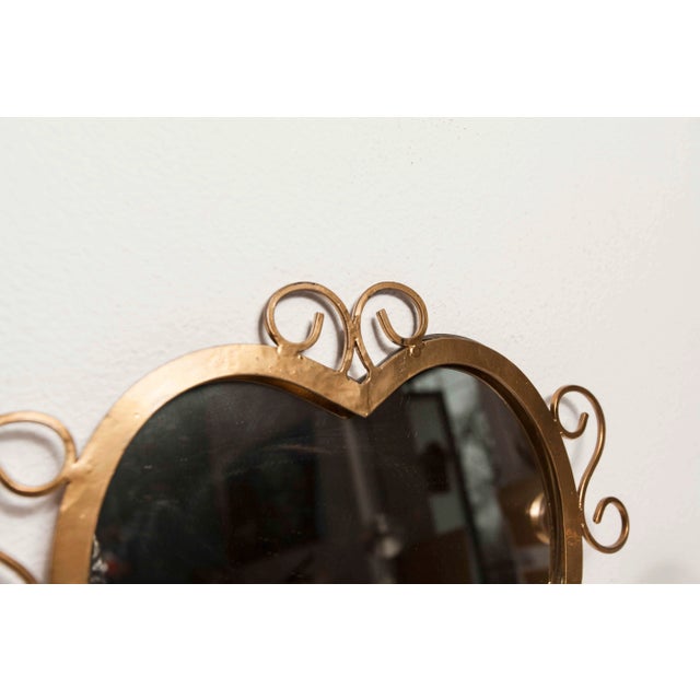 Handcrafted 1960's wall mounted coat rack with heart shaped central mirror. It has 2 coat hooks and is solid and gold in...