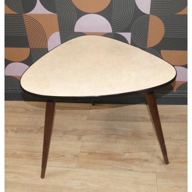 Kidney-shaped cocktail table from the 1950s. The table stands on three sturdy, tapered legs with brass finials. The pastel...