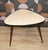 Kidney-shaped cocktail table from the 1950s. The table stands on three sturdy, tapered legs with brass finials. The pastel...