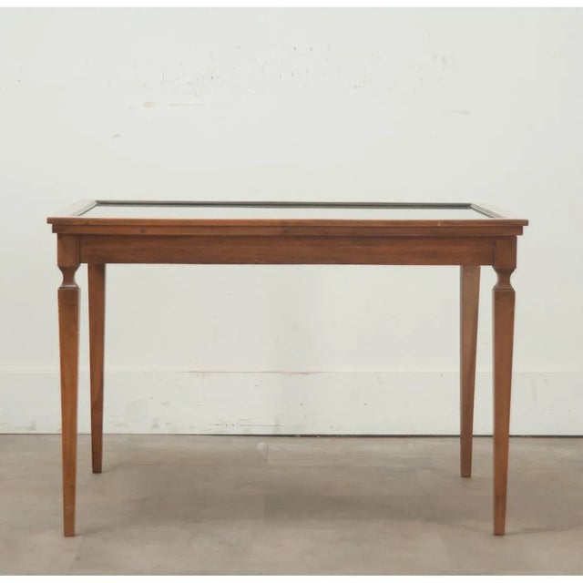 A French vintage coffee table with a mahogany frame and glass top. This unique table currently features a 19th century...