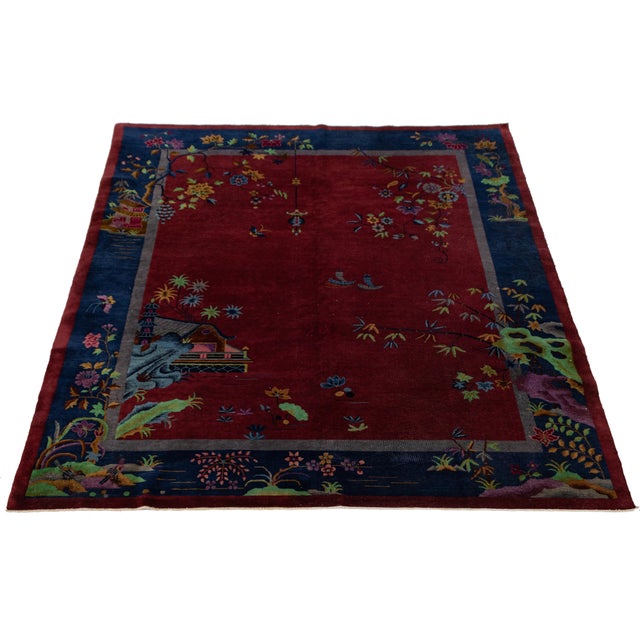 This antique Chinese Art Deco wool rug from the 1920s features a vivid red field framed by deep indigo borders, showcasing...