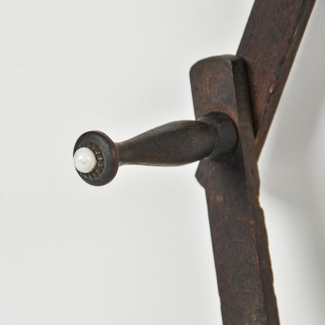 Beautiful dark wood antique accordion peg rack. Each peg is tipped with a white glass or porcelain button. Ten pegs all...