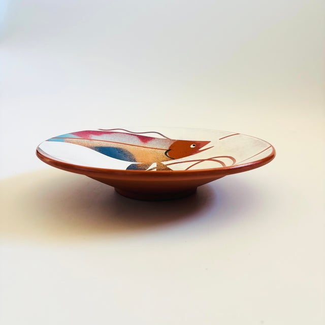 A vintage studio pottery plate. Terra cotta color to the clay with a beautiful hand painted design of a fish to the...