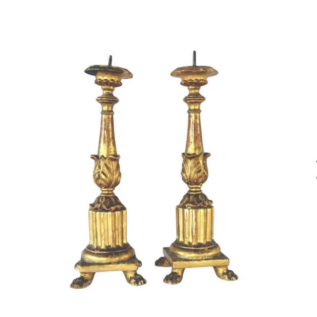 A Pair of Italian Carved and Gilded Candlesticks that embody the elegance of classical design. Each candlestick rises from...