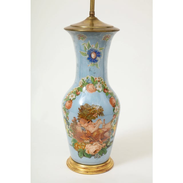 Featuring a floral wreath of roses, hydrangea, and daffodils encircling a classical maiden in deshabille, set below a...