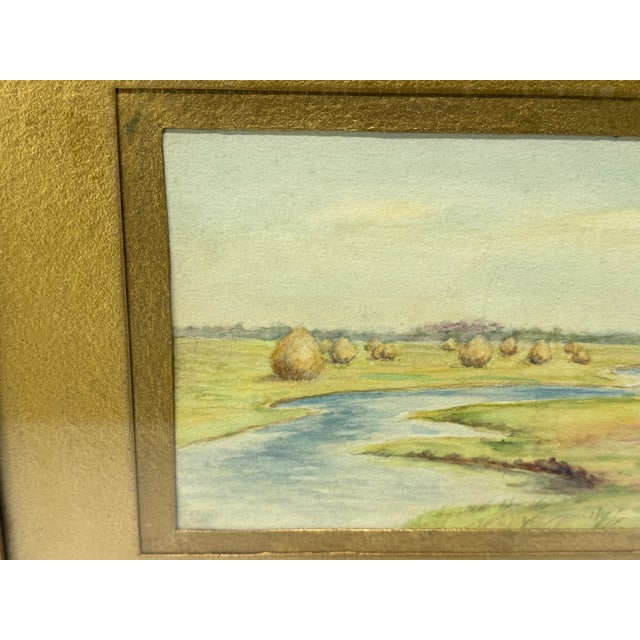 This finely executed watercolor painting depicts a tranquil pastoral landscape, featuring a gently winding river bordered...