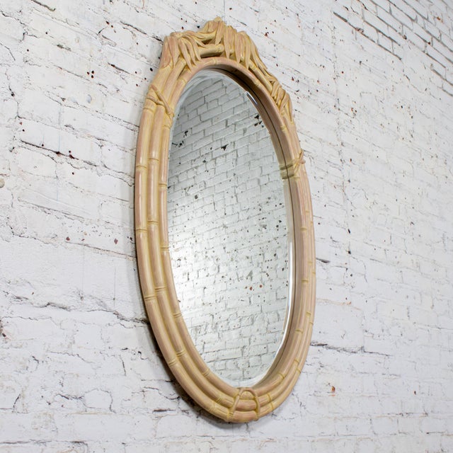 Lovely vintage Coastal or Hollywood Regency style oval wall mirror composed of faux bamboo resin frame with cerused or...