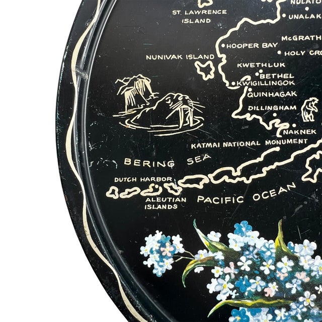 A mid century metal serving tray decorated with Alaskan tourist spots and the outline of Alaska with its towns and...