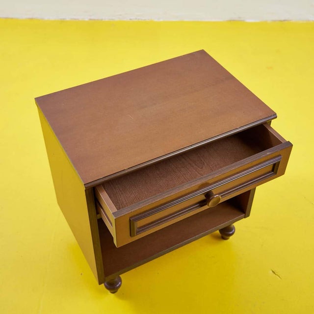 This refined solid wood bedside table, dating back to the 1960s, is a distinctive piece of vintage design. Featuring a...