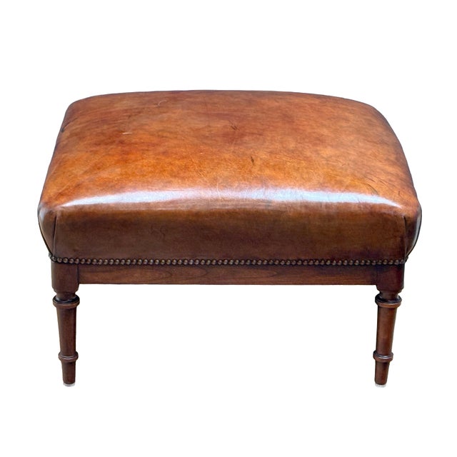 A fine French ottoman or stool, featuring a handsome upholstered seat of hand-dyed brown leather, with nail-head trim...