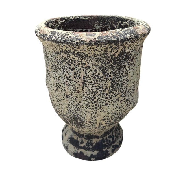 A vintage terracotta garden planter featuring a heavily textured volcanic glaze in layered charcoal, cream, and earthy...