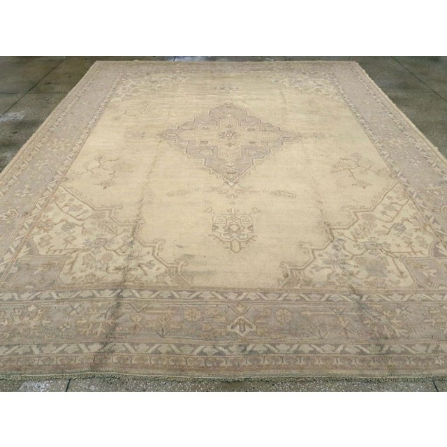 An antique Turkish Oushak room size carpet. This soft-colored western Turkish workshop Oushak is in the Heriz style with a...