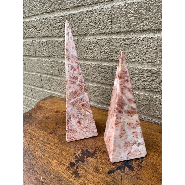 A beautifully proportioned pair of marble obelisks in richly veined shades of pink and cream. The sculptural silhouettes...