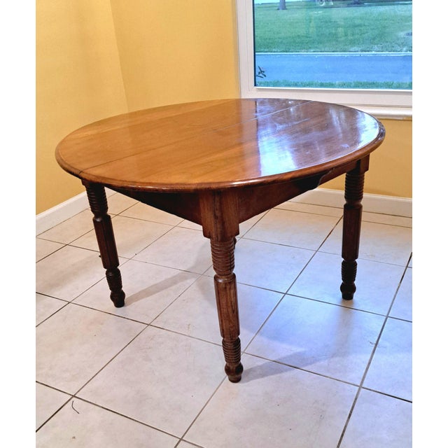lassic antique round dining table with a warm mahogany finish and handsome turned legs. The piece has a simple farmhouse...