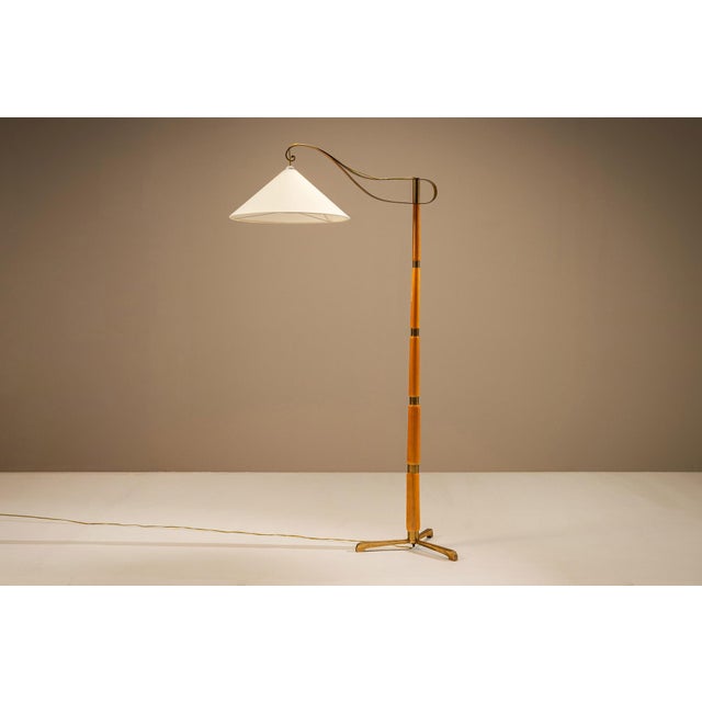 A slender composition of wood, brass and light, this floor lamp captures the restrained character of Swedish Modern...