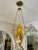 This beautiful triangle brass cast pendant has beautiful golden color piece of handblown glass in the upper part. The...