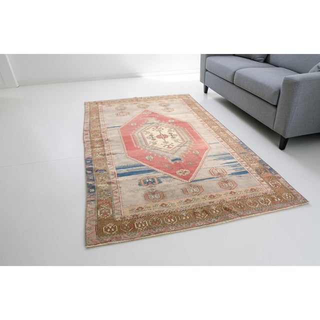 This is a vintage Turkish Oushak rug from the Mid 20th Century. The piece was hand-knotted.