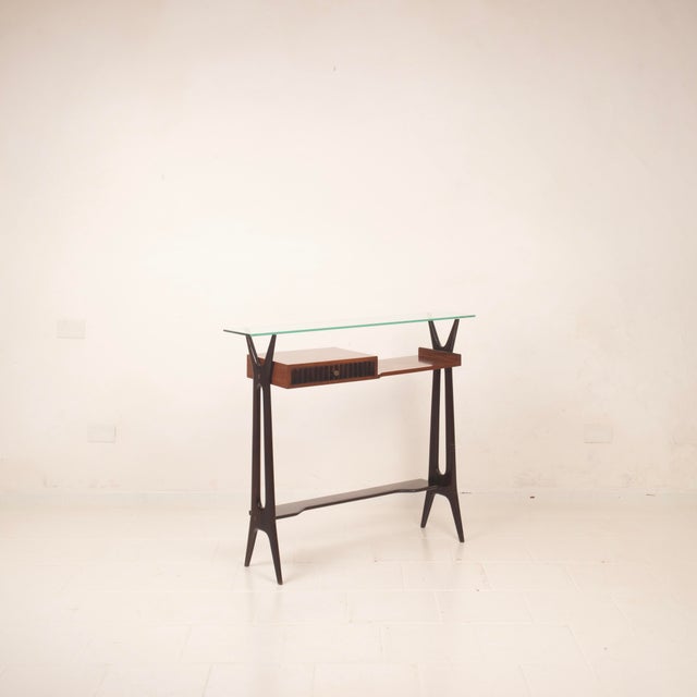 Elegant console made in Italy during the 1950s, with a rosewood structure, ebonized Maple, and a glass top. The designer...