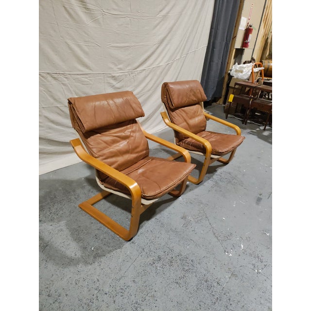 A striking pair of Italian mid-century modern sling lounge chairs, circa 1960. These chairs feature beautifully sculpted...
