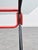 Vintage table with a strong retro feel, featuring a rectangular clear glass top and a black tubular metal frame with red...