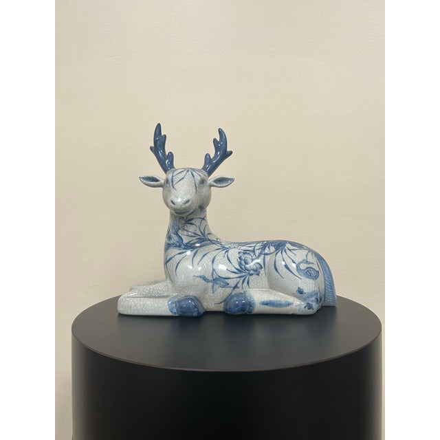 A large late 20th century Thai ceramic deer figurine hand-painted in cobalt blue and white beneath a glossy crackle glaze....