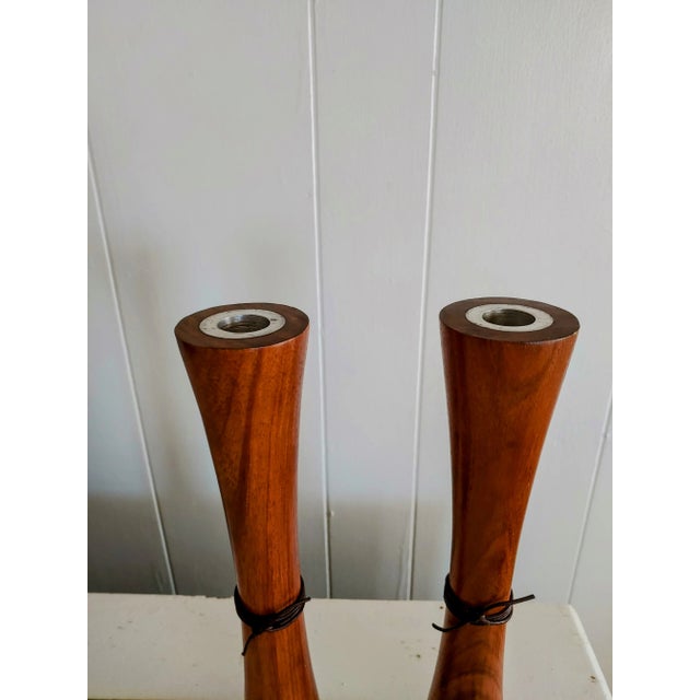 Here's a fine and unusual pair of teak wood candleholders in the Danish Modern style that feature double ended stainless...