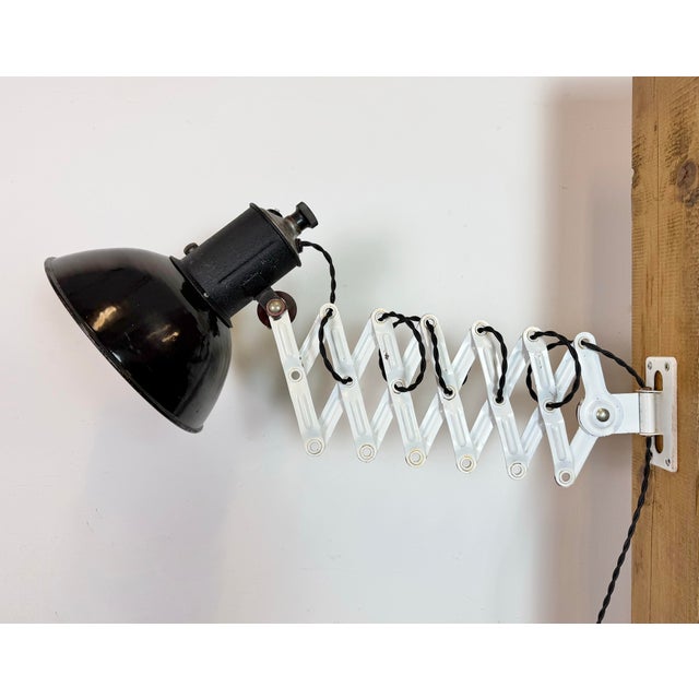 This vintage Industrial adjustable scissor wall lamp was produced in former Czechoslovakia during the 1950s. The lamp has...