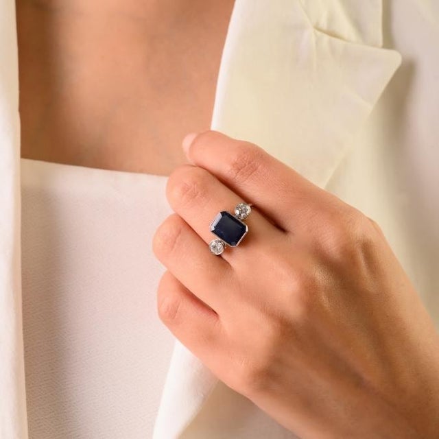 This elegant Art Deco-style three-stone ring features 1 octagon cut blue sapphire totaling 3.33 carats, set in rich 18K...