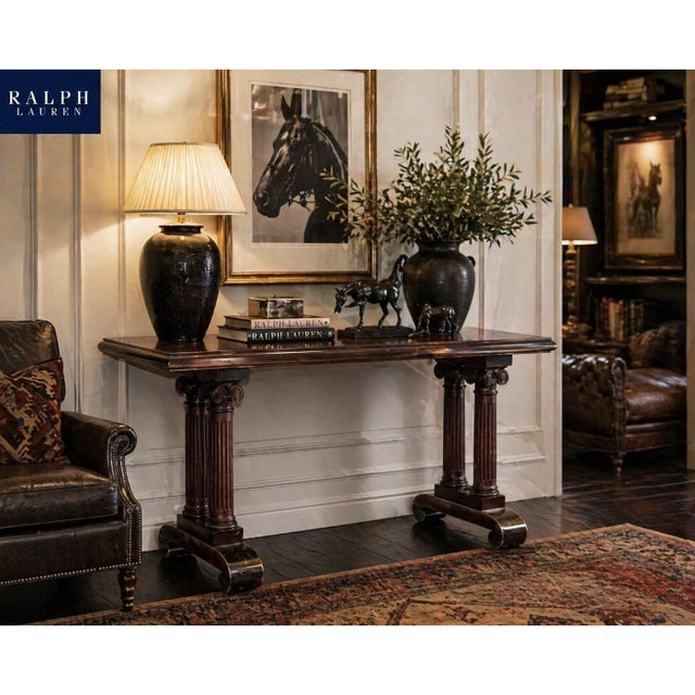 A striking Neoclassical-inspired console table featuring a refined double pedestal base with fluted column legs and Ionic-...