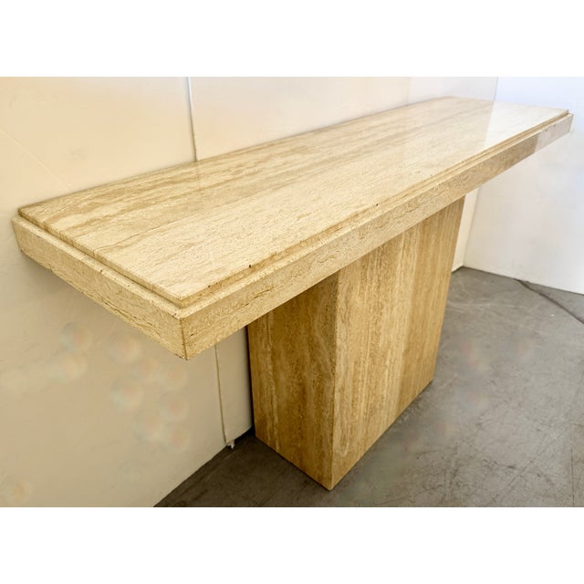 1980s Italian travertine console table, featuring a rectangular top and a single pedestal base. A minimalist piece crafted...