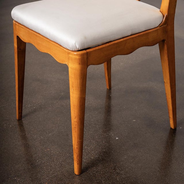 A set of six Italian mid-century dining chairs featuring warm walnut frames and a subtle scalloped detailing with elegant,...