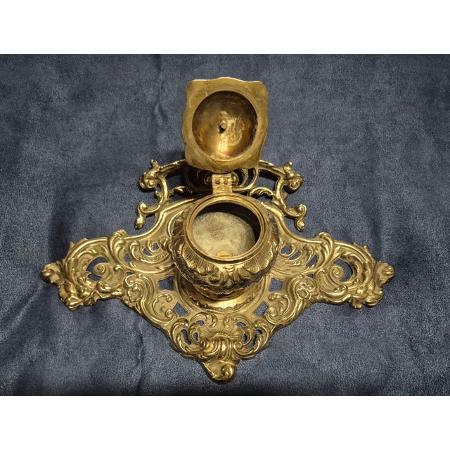 This item is an ornate cast brass inkwell stand crafted in the elaborate Rococo Revival style, typically dating from the...