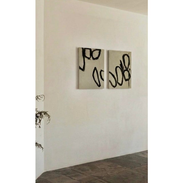 This set of two original abstract oil paintings by artist Tina Shenk features bold black forms on a warm neutral muted...