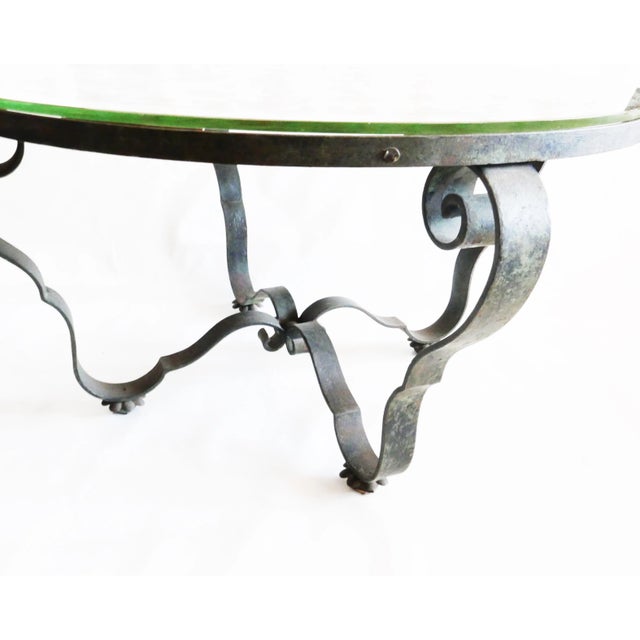 Late 1940s table with églomisé glass decoration Wrought iron base with patina finish, églomisé glass top with late 1940s...